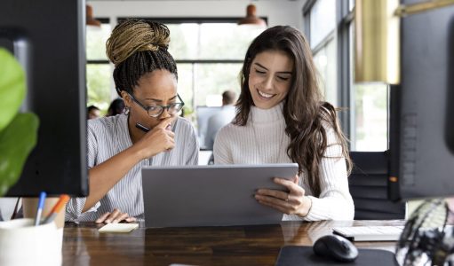 Mid adult women use a local co working space to meet together and design newsletter layouts for their business.